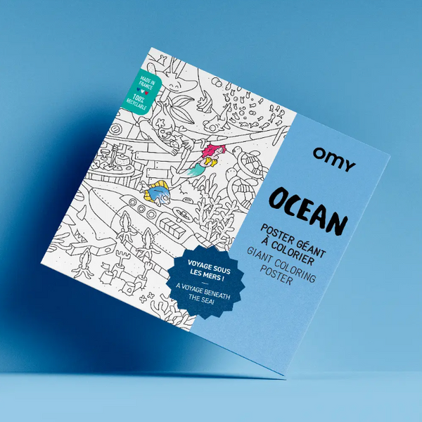 A boxed coloring poster product titled 'OCEAN' by omy, shown at an angle on a blue gradient background. The package is light blue and white, with black text and an ocean-themed line drawing on the front.